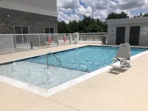 费耶特维尔Holiday Inn & Suites - Fayetteville W-Fort Bragg Area, an IHG Hotel的一个带椅子和椅子的大型游泳池