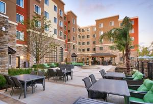 盖恩斯维尔Staybridge Suites - Gainesville I-75, an IHG Hotel的庭院内带桌椅的庭院。