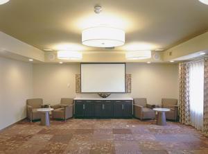 柯林斯堡柯林斯堡烛木套房酒店的大房间设有屏幕和椅子,大房间设有大屏幕