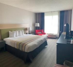 休斯顿Sonesta Essential IAH Airport JFK Boulevard - Newly Renovated的酒店客房设有一张大床和一张红色椅子。