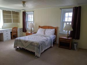 Smoketown云杉巷小屋宾馆的一间卧室设有床、两张桌子和两个窗户。