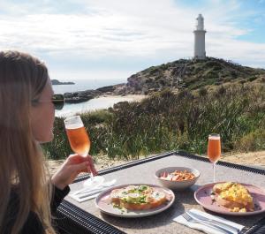 罗特内斯特岛Discovery Resorts - Rottnest Island的坐在餐桌旁的女人,带着食物和灯塔