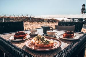 罗特内斯特岛Discovery Resorts - Rottnest Island的海滩上一张桌子,上面放着盘子和咖啡