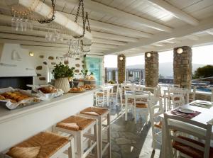 奥诺斯莱奥尼斯夏季别墅酒店的餐厅设有早餐吧,配有白色凳子