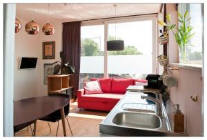 阿姆斯特丹Private guesthouse BnB The Waterhouse houseboat的客厅配有红色的沙发和桌子