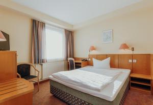 奥斯纳布吕克克鲁特酒店的酒店客房设有一张大床和一张书桌。