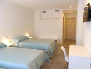 蒙蒂霍Hotel Gran Sol De Extremadura的客房设有两张床、一张桌子和电视。