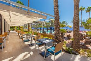 圣阿古斯丁Corallium Beach by Lopesan Hotels - Adults Only的一间带桌椅和海滩的餐厅