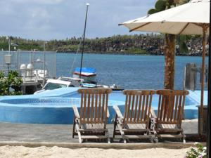 阿约拉港海湾之家乡村别墅的游泳池旁的两把椅子和一把遮阳伞,设有一艘船