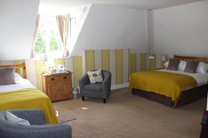 戈斯兰Fairhaven Country Guest House的一间卧室设有两张床、一把椅子和一个窗户。