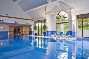 东基尔布赖德假日格拉斯哥东基尔布莱德酒店的大楼内带蓝色椅子的游泳池