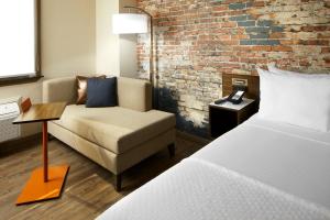 达拉姆The Lodge at Duke Medical Center的一间设有床、沙发和砖墙的房间