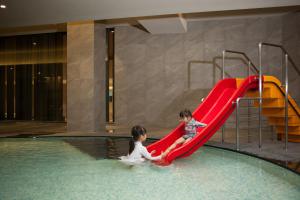 江陵市拓扑斯10号酒店的两个孩子在游泳池滑梯上玩耍
