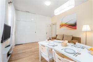 奥帕提亚罗纳奥帕蒂亚高级公寓的白色的用餐室配有白色的桌椅
