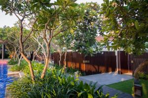 库塔巴厘岛安瓦雅海滩度假酒店的一座种植了树木的花园、围栏和游泳池
