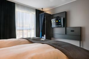 曼海姆Holiday Inn - the niu, Square Mannheim, an IHG Hotel的卧室配有一张床铺,墙上配有电视