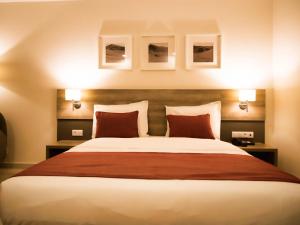 努瓦克肖特蒙诺特尔达尔巴尔卡酒店的一间卧室配有一张带红色枕头的大床