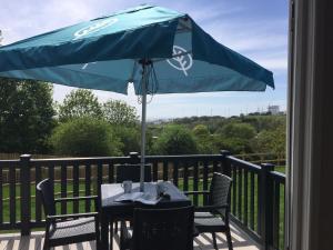 布莱顿霍夫Brighton Experience Freedom Glamping的甲板上的一张带蓝色遮阳伞的桌子