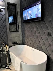 乔左维尔考普尔斯基Hotel Fado的带浴缸的浴室以及墙上的电视