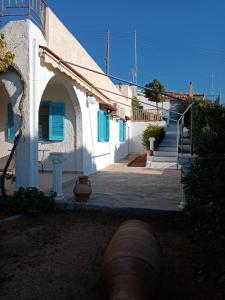 SpiliazézaBeautiful Island house with sea view的白色的建筑,设有蓝色的窗户和楼梯