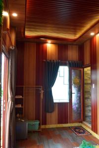 河仙Hà Tiên Homestay的一间设有木墙和窗帘的窗户的客房
