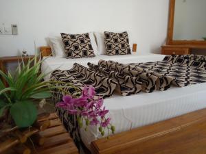 达瓦拉维加扬的酒店的一张铺有黑白床单和紫色花卉的床
