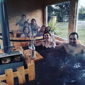 PuqueldónLodge Guarida del Trauco的一群人在带酒杯的热水浴缸中