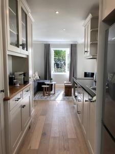 开普敦Garden Cottage - Leafy Constantia Guest House的厨房铺有木地板,配有白色橱柜。