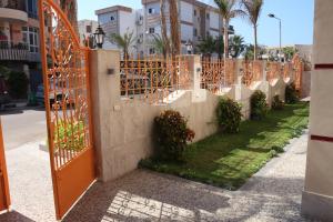 亚历山大Al Raya Apartments的种植着植物的栅栏中的橙色门