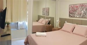萨尔瓦多FANTÁSTICO APARTAMENTO NA BARRA的一间卧室配有两张带粉红色枕头的床