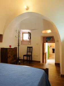 马丁纳弗兰卡Trullo Chiari di Bosco的一间卧室设有拱门、一张床和一把椅子
