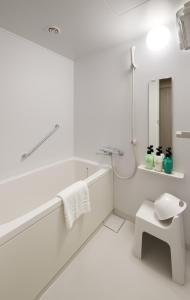 东京Hotel Crown Hills Ueno Premier的白色的浴室设有浴缸和水槽。