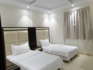 塞卡凯Fakhamat Al Orjoana & Suites的配有2张床的白色墙壁和窗户。