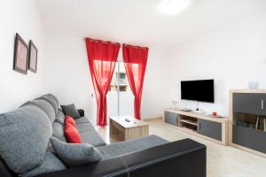 坎德拉里亚Home2Book Charming Apartment Candelaria, Wifi & Pool的客厅配有灰色的沙发和红色窗帘