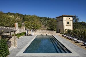 佛罗伦萨Torre a Cona Wine Estate的一座带椅子的庭院和一座建筑中的游泳池