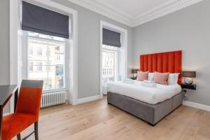 爱丁堡Destiny Scotland Hanover Apartments的一间卧室配有一张带橙色床头板的大床