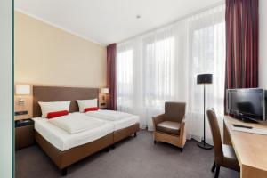 慕尼黑ACHAT Hotel München Süd的一间卧室配有一张床、一张书桌和一台电视