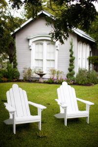 RockdaleRainbow Courts的两把白色椅子坐在房子前面的草上