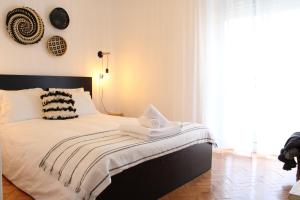 科英布拉Bela Casa - Modern Designer Chic Central Coimbra的一间卧室配有一张带白色床单的床和一扇窗户。