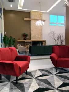 新彼得罗波利斯Hotel Alles Berg的客厅配有2把红色椅子和壁炉