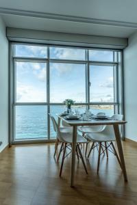 拉科鲁尼亚APARTAMENTO CON INCREIBLES VISTAS A LA PLAYA DE RIAZOR的一间带桌椅和大窗户的用餐室