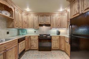 爱德华兹Cozy & Central Arrowhead Village Townhome Condo的厨房配有木制橱柜和黑色冰箱。