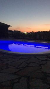 康塞高伊比蒂波卡Chalés Alternativa的夜晚的蓝色海水泳池与日落