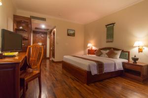 暹粒克马拉吴哥温泉酒店的一间卧室配有一张床、一张书桌和一台电视