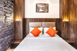 孟买Hotel Sea Grand, Colaba的一间卧室配有带橙色和白色枕头的床