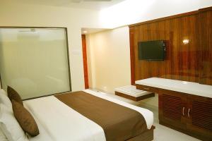 孟买米兰国际大酒店的一间卧室配有一张大床和电视