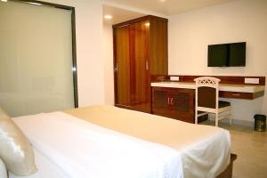 孟买米兰国际大酒店的一间卧室配有一张床和一张书桌及电视