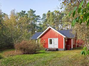 维斯特索马肯6 person holiday home in Aakirkeby的院子里有红色的棚子,有白色的门