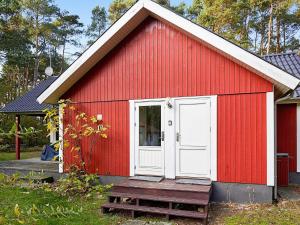 维斯特索马肯6 person holiday home in Aakirkeby的红色的棚子,有白色的门和门廊