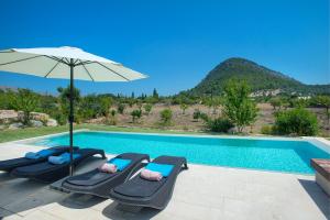 埃尔波特Owl Booking Villa La Rafal - Luxury Retreat with Mountain Views的一个带2把躺椅和遮阳伞的游泳池